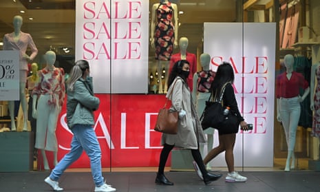 People walk past sales signs in a retail store in Sydney, Australia