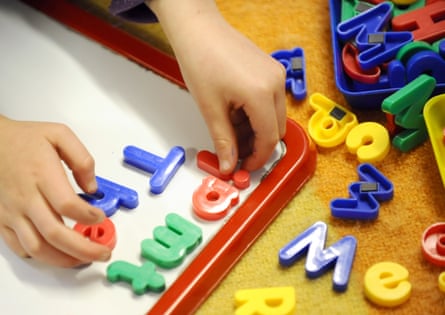 A child plays with plastic letters of the alphabet, placing them on a board