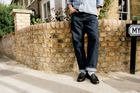 Tim’s legs, in jeans, white socks and nice black loafers, on a London residential street