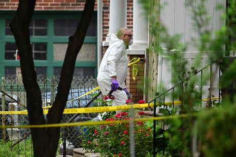 An FBI investigator in a hazmat suit stands near a doorway behind police tape