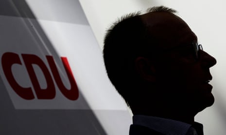 Shadowed profile of Friedrich Merz, leader of Germany's CDU party, with a CDU logo hanging behind him