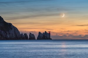 Crescent Moon over the Needles Ainsley Bennett (UK). The 7% waxing crescent Moon setting in the evening sky over the Needles Lighthouse at the western tip of the Isle of Wight. Despite the Moon being a thin crescent, the rest of its shape is defined by sunlight reflecting back from the Earth’s surface