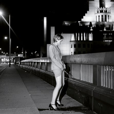 Black and white photograph of a woman in a smart skirt suit on a bridge urinating like a man