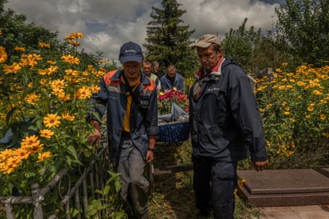 The body of a woman killed in a Russian strike is carried through a flower filled cemetery to her grave on the outskirts of the Kreminna forrest (July 2023).