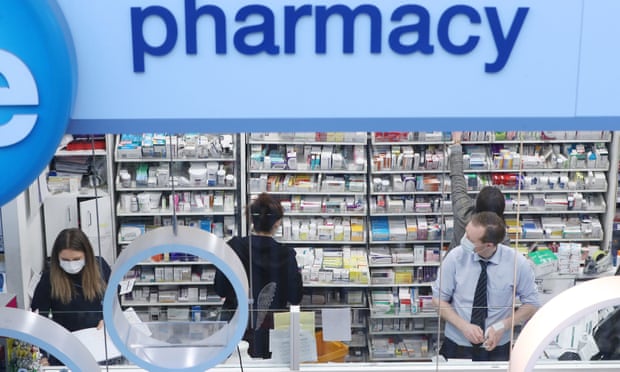 Pharmacists at work behind counter in a shop.