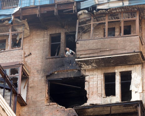 A man looks out of a broken window at the site of a drone strike in Kyiv, Ukraine.