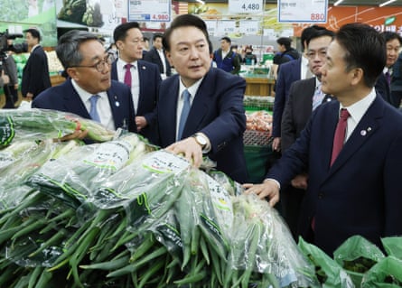 South Korean president Yoon Suk Yeol (C) visits a Hanaro Mart branch to check the price of green onions in Seoul.