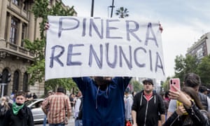 A demonstrator holds a sign reading ‘Piñera, quit’ during the protest against the rise in public transport fares in Santiago, Chile.