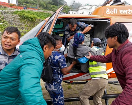 a woman being carried by several men into a waiting helicopter