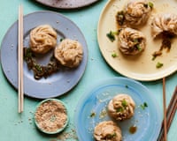 plates of momos with chopsticks and sesame sprinkled on a green table