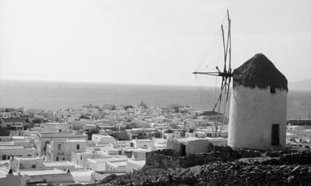 Windmill in foreground; white houses and sea behind (black and white photo)