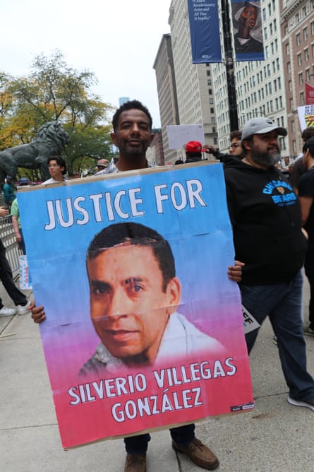 man holds up sign at protest saying ‘justice for silverio villegas gonzalez’ with a photo of a man