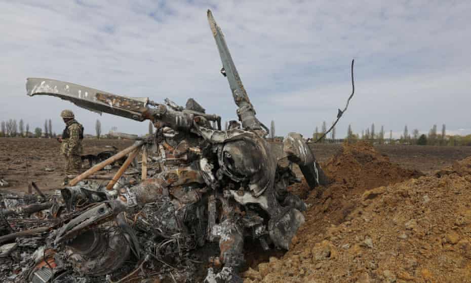 A Ukrainian serviceman near the remains of a Russian Mi-8 helicopter that crashed near Kyiv