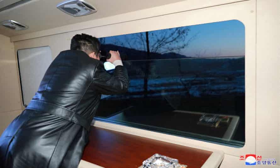 Kim Jong-un watches the test launch through binoculars.