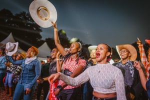 People in western wear listen to live country music