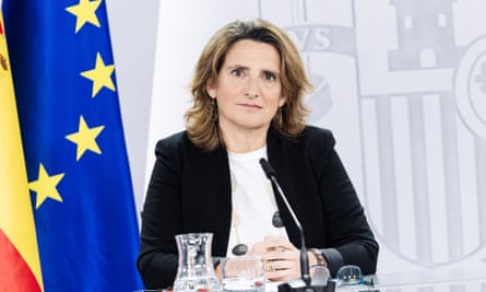 Teresa Ribera sitting at a table with an EU flag beside her