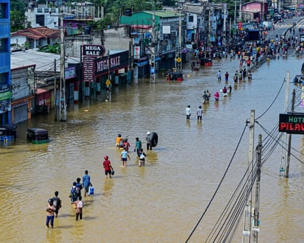 People wade through a flooded street after heavy rainfall in Wellampitiya, on the outskirts of Colombo