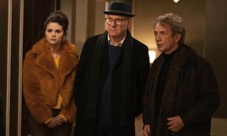 Selena Gomez, dressed in a brown faux fur coat, Steve Martin, dressed in a dark coat and fedora, and Martin Short, dressed in a brown jacket and scarf, face the camera in a still from Only Murders in the Building