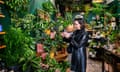 A woman inspects plants in a floral shop.