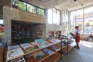 a child stands and looks through a book at a library table displaying dozens of other books