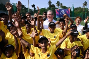 Keir Starmer laughs, surrounded by boys in yellow shirts with their arms in the air