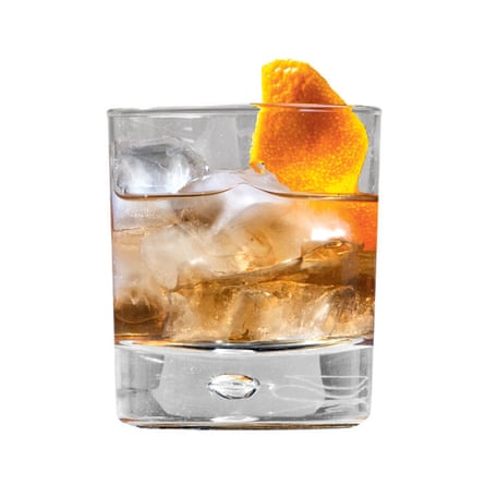 A tumbler containing a brown cocktail with ice cubes and an orange peel garnish