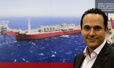 Wael Sawan poses for a photograph beside a picture of a ship