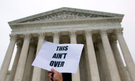 A demonstrator outside the US supreme court with a placard that reads: 'This ain't over'