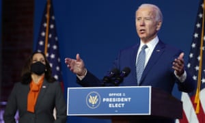 joe biden speaks at a lectern with kamala harris looking on
