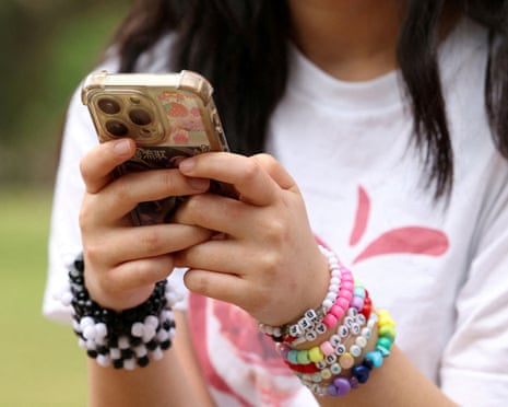 Girl holding a mobile phone while talking about Australia's social media ban for under-16s