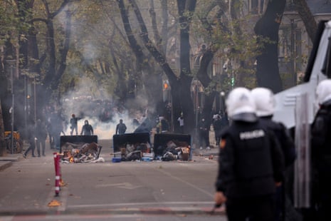 Police officers in riot gear stand near demonstrators behind overturned dustbins with burning rubbish during an anti-government protest by students in Tirana, Albania, 24 October, 2026.