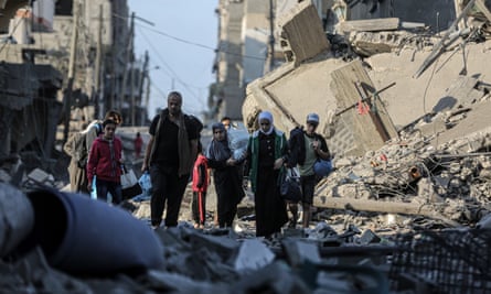 People carrying belongings between bombed buildings