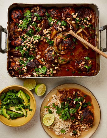 Spicy chipotle chicken in a rectangular metal pan with handles, a bowl of avocado, a lime sliced in half and a plate of black-eyed bean salsa