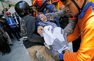 Rescue workers – some wearing orange and blue, and in hard hats or helmets – carry a distressed person