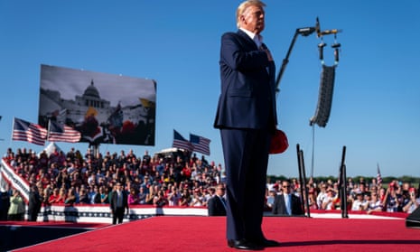 Donald Trump places his hand on his heart as footage from the January 6 Capitol riot is displayed in the background at Waco, Texas, on Saturday.
