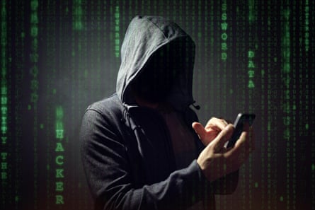 A person in a grey hoodie, face unseen, holding a mobile phone