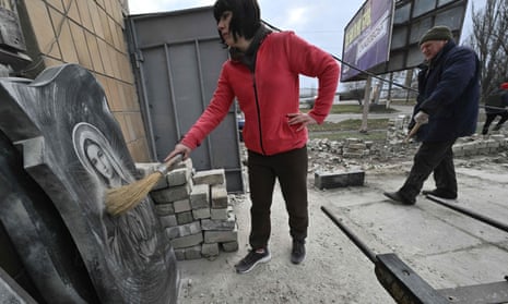 A woman clears gravestones in a shop damaged following a Russian strike in Kherson, Ukraine