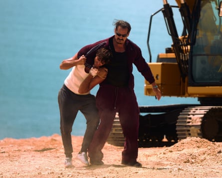 man holds another man in a chokehold by a bulldozer on television set