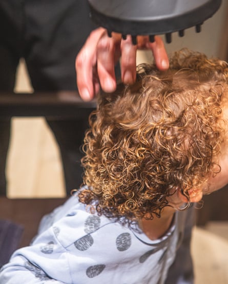 A child with an adult’s hand in her hair