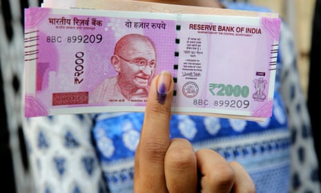 An Indian girl shows her inked finger as she holds one of the new Indian currency notes at a bank in Bhopal, Madhya Pradesh.