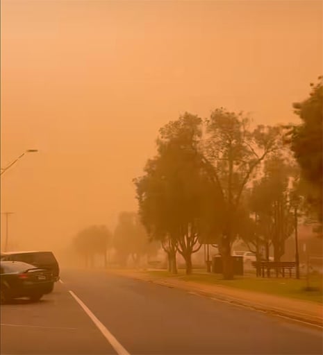 A town is covered in an orange cloud of dust during a storm.