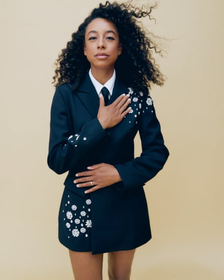 A woman in a black suit dress with diamante detailing on a sleeve and shoulder.