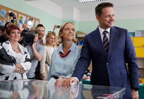 Warsaw's Mayor and member of the ruling centrist Civic Coalition Rafał Trzaskowski (R) and his wife, Małgorzata Trzaskowska, (C) cast their votes at a polling station in Warsaw, Poland, during the second round of the presidential elections.