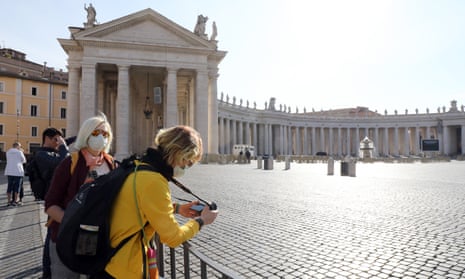 People stand behind barriers in an empty St Peter’s Square in Rome. The aim of flattening the curve is to avert a situation such as in Italy which has been overwhelmed by a spike in cases.