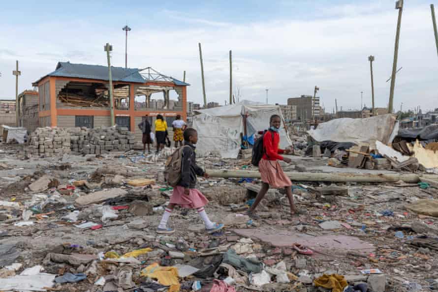 Children walk past a partially demolished school in Mukuru Kwa Njenga