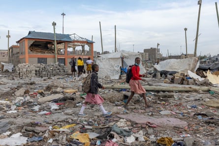Children walk past a partially demolished school in Mukuru Kwa Njenga