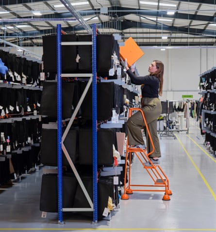 Vestiaire Collective authenticator Justine Bammez up a ladder at their warehouse in Crawley, UK