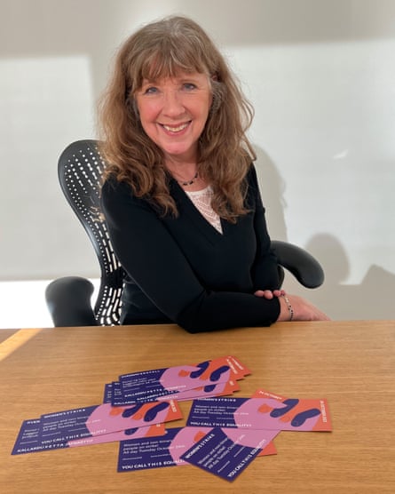 Kolbrún Halldórsdóttir, now 68, sitting in an office chair behind a desk on which there are leaflets promoting the 2023 women’s strike, and smiling
