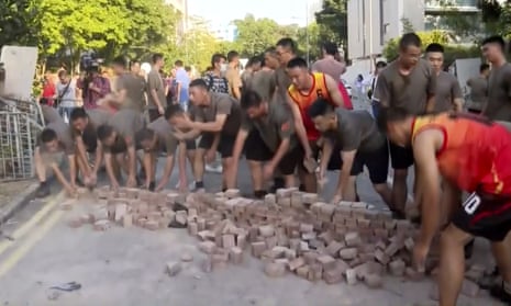 People’s Liberation Army soldiers, dressed in shorts and T-shirts pick up bricks scattered by protesters at Hong Kong Baptist University in Hong Kong