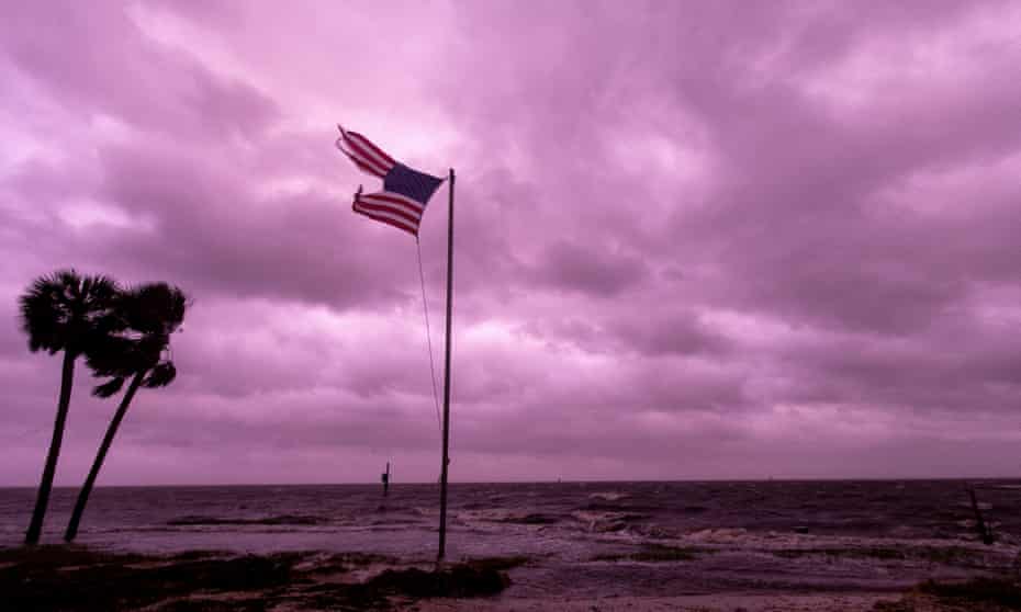 An American flag battered by Hurricane Michael continues to fly in the in the purple colored light of sunset at Shell Point Beach on October 10, 2018 in Crawfordville, Florida.